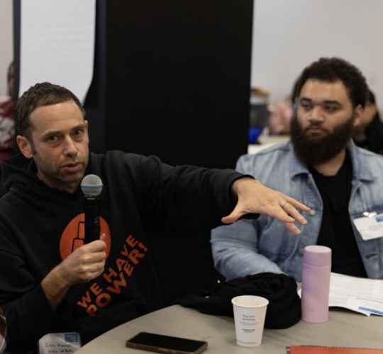 Man on a microphone speaking to a group